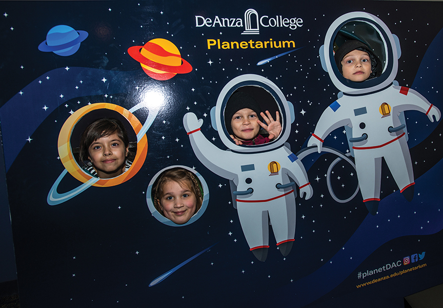 Children sticking their heads out of an asronaut and space cutout